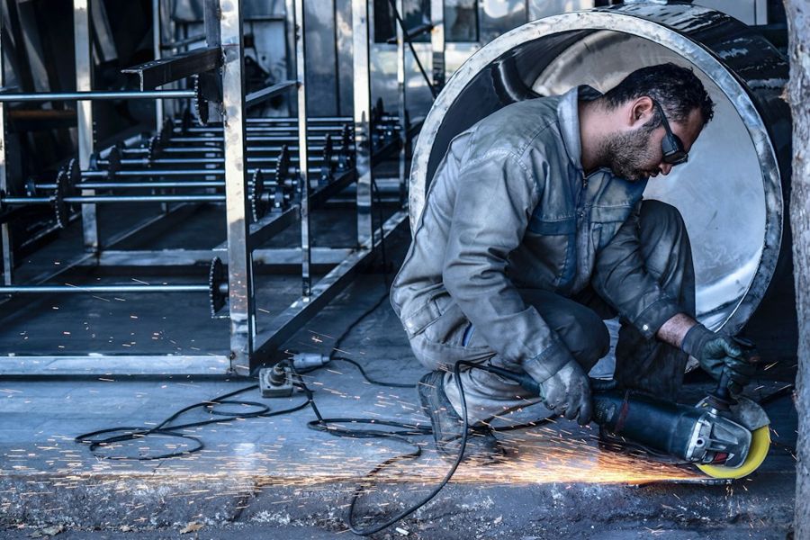 Fabricator grinding a stainless steel drum
